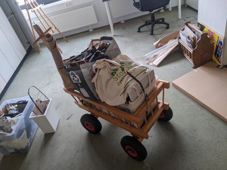 photo of a handcart piled with bags of art supplies in the middle of a room