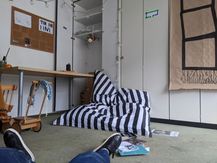 view of a black and white striped bean bag, with my legs and shoes in the foreground