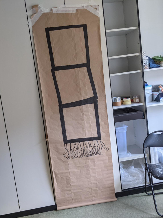 a piece of packing paper taped to a wardrobe door. on it is drawn a stack of three squares carried on a profusion of legs